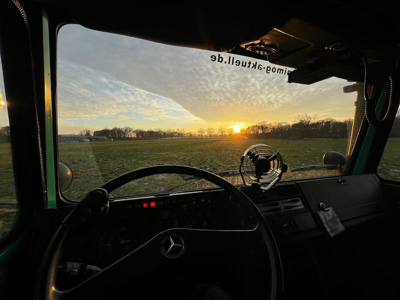 Blick aus dem Fahrerhaus eines Unimogs in den Sonnenuntergang