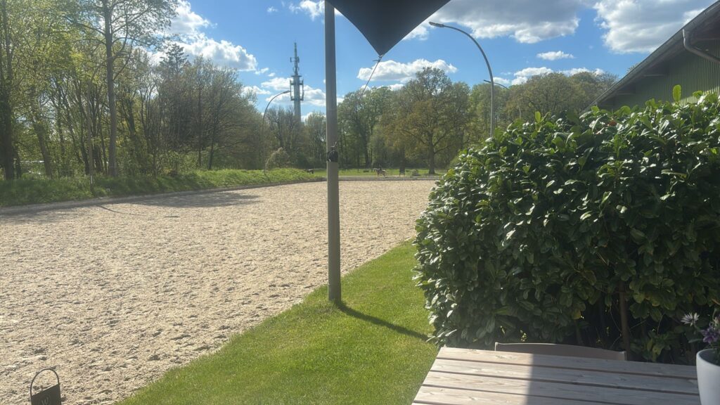 Blick von der Terrasse der Hofküche auf den großen Außenplatz Dressur der Reitanlage Gut Tangstedt