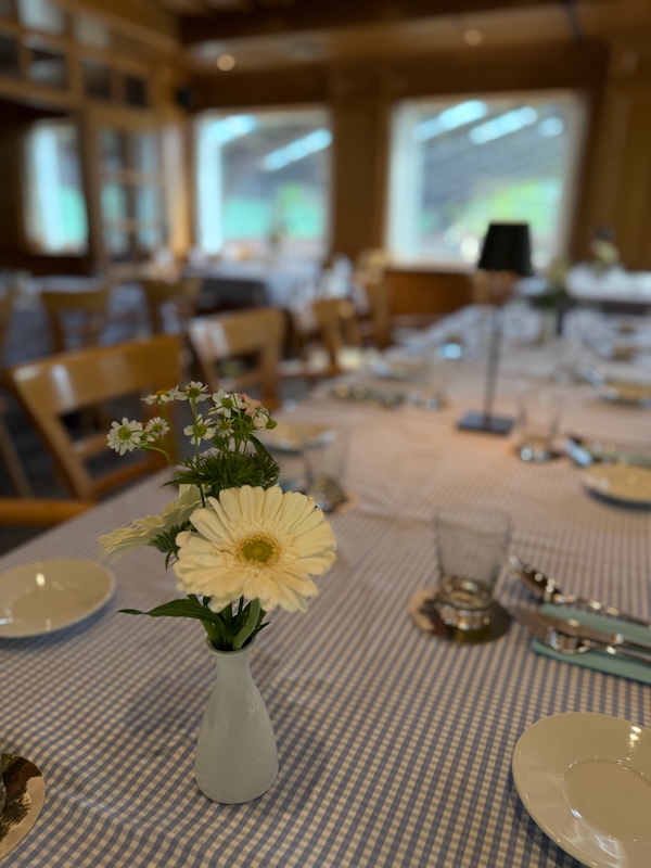 Vase mit frischen Blumen auf einem für eine Feier eingedeckten Tisch