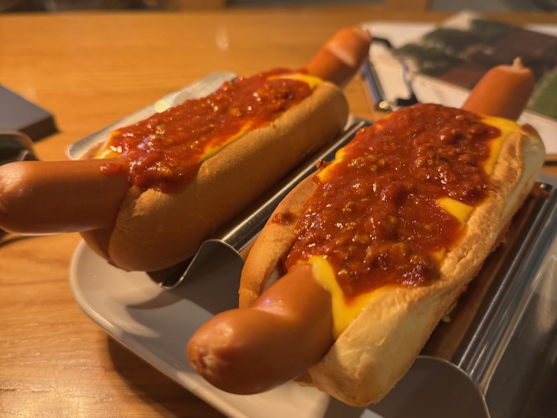 Zwei Chilli Cheese Dogs auf einem Metallständer angerichtet
