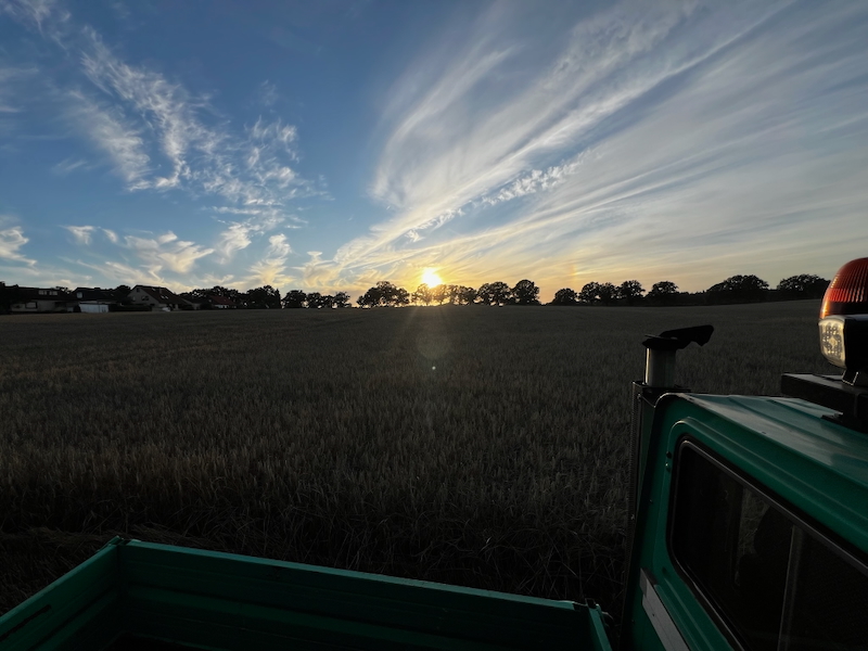 Sonnenuntergang bei der Strohernte 2025 über einem Acker in Tangstedt Dorf