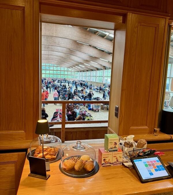 Blick aus der Hofküche in die Springhalle beim Reitflohmarkt, im Vordergrund Kaffee, Kuchen und belegte Brötchen für den Außer-Haus-Verkauf.