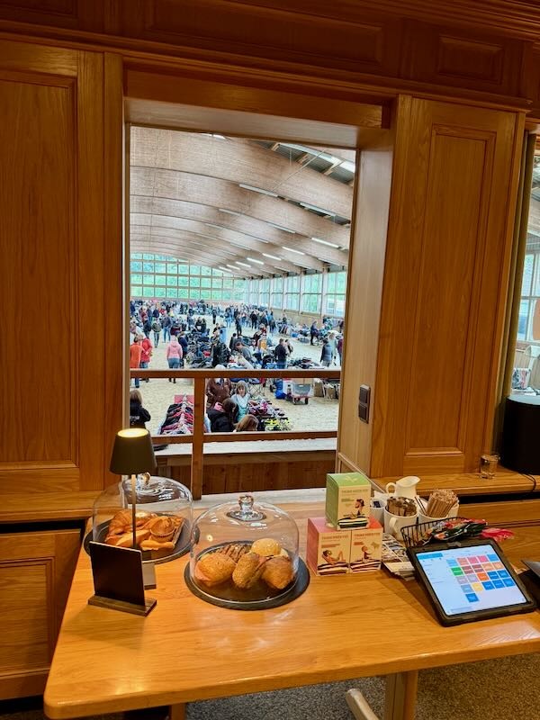 Blick aus der Hofküche in die Springhalle beim Reitflohmarkt, im Vordergrund Kaffee, Kuchen und belegte Brötchen für den Außer-Haus-Verkauf.
