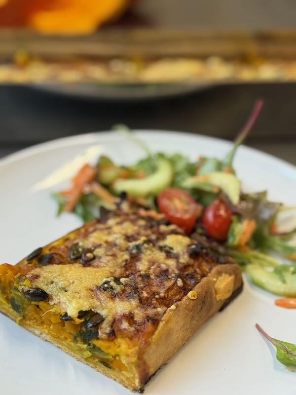 Herzhafte Kürbis-Quiche mit Salatgarnitur, serviert in der Hofküche Gut Tangstedt