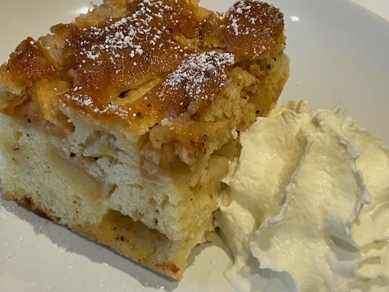 Apfelkuchen mit Sahne auf einem Teller, frisch gebacken in der Hofküche auf Gut Tangstedt