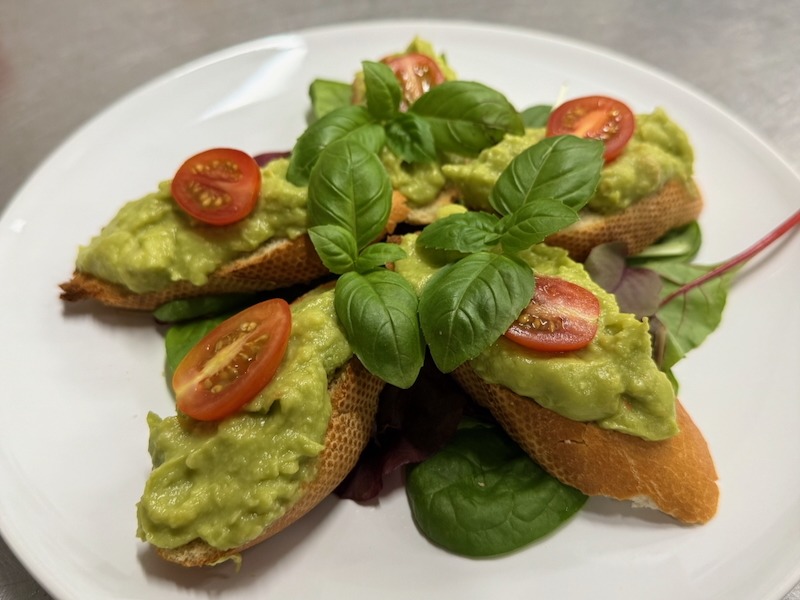 Hausgemachte Crostini mit cremigem Avocado-Aufstrich, Kirschtomaten und frischem Basilikum aus der Hofküche Gut Tangstedt