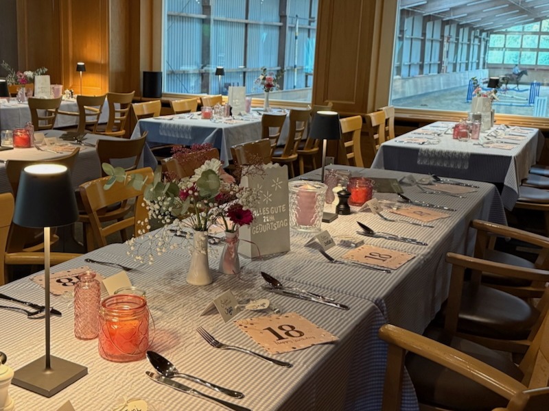 Festlich gedeckter Tisch in der Hofküche Gut Tangstedt für eine Geburtstagsfeier mit Blumen, Kerzen und Blick in die Reithalle