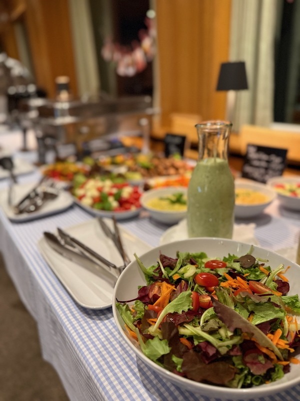 Salatbuffet mit Dressing und frischen Zutaten wie Tomaten, Karotten und Blattsalat – Hofküche Gut Tangstedt