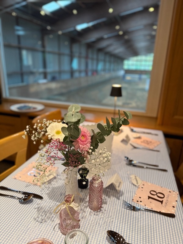 ischdekoration mit frischen Blumen, Kerzen und Geburtstagskarten am Fenster mit Blick in die Reithalle – Hofküche Gut Tangstedt