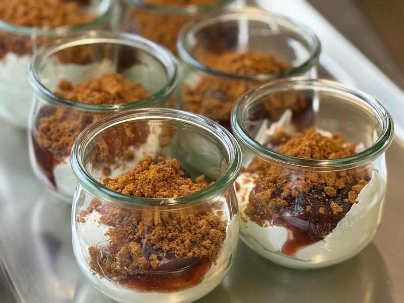 Topfencreme im Glas mit Zwetschgenkompott und knusprigem Crumble, frisch vorbereitet in der Hofküche auf Gut Tangstedt.