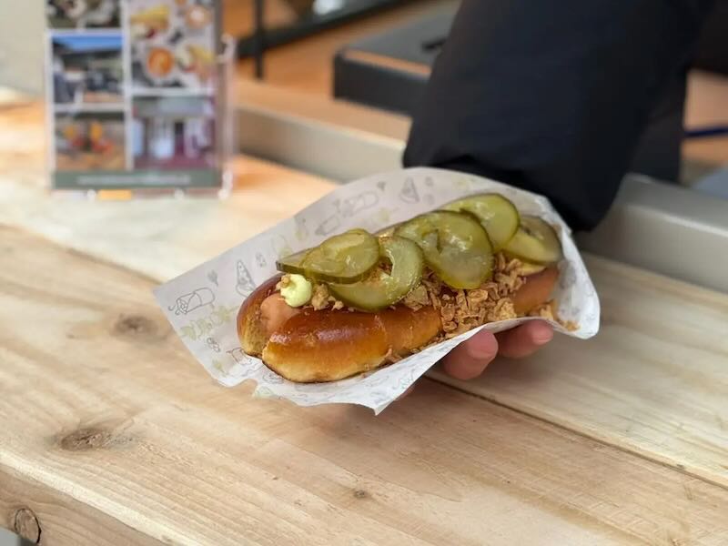 Hot Dog mit Senf, Ketchup, Remoulade, gerösteten Zwiebeln und Gewürzgurke