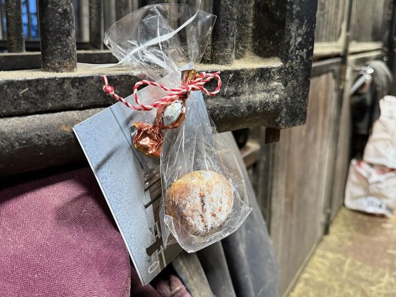 Weihnachtlich verpackte Stollen-Tüte mit roter Kordel, als kleiner Gruß an einer Pferdebox im Stall von Gut Tangstedt befestigt.
