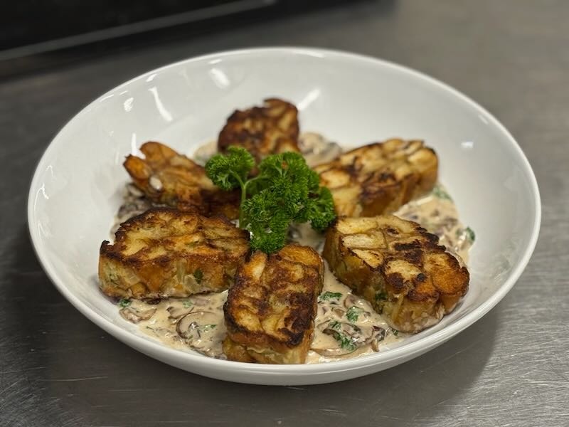 Hausgemachte Brezelknödel auf cremigem Pilzragout, angerichtet in der Hofküche auf Gut Tangstedt.