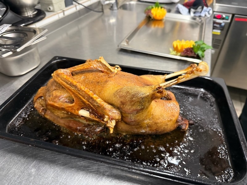 Ganzer, knusprig gebratener Gänsebraten in der Fettpfanne, frisch zubereitet für ein festliches Weihnachts-Essen.