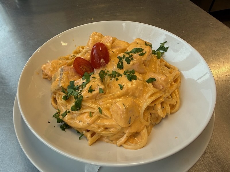 Caesar-Wrap mit Hähnchen, frischem Salat, Tomaten und Champignons, angerichtet auf einem Teller in der Hofküche auf Gut Tangstedt.