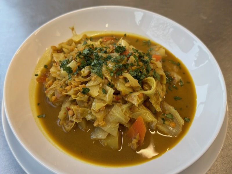 Caesar-Wrap mit Hähnchen, frischem Salat, Tomaten und Champignons, angerichtet auf einem Teller in der Hofküche auf Gut Tangstedt.