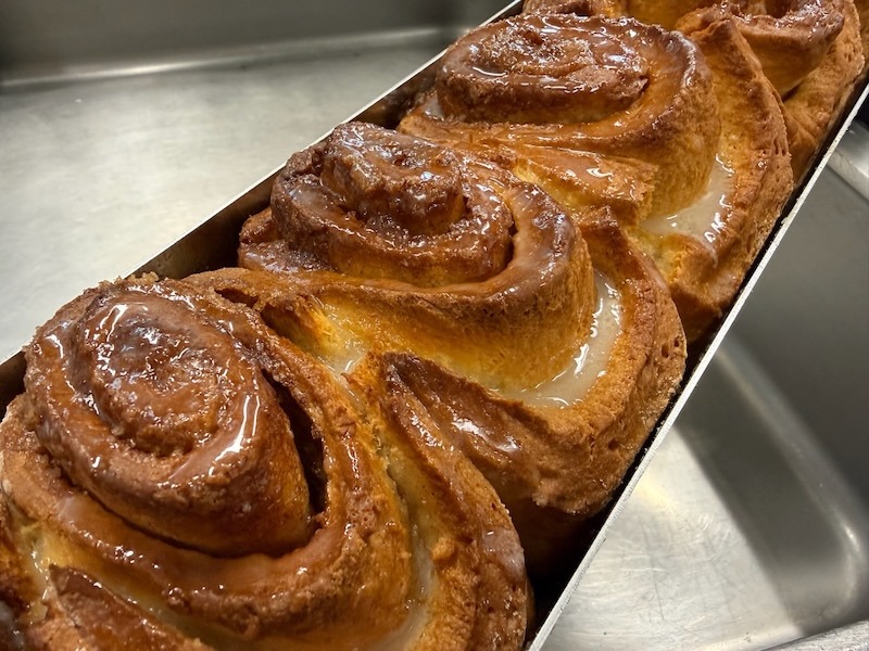 Frisch gebackene Zimtschnecken mit Zuckerglasur in einer Backform, hausgemacht in der Restaurantküche.