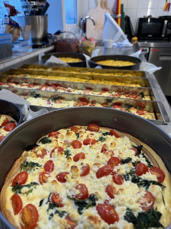 Detailansicht einer herzhaften Quiche mit Kirschtomaten, Schafskäse und Blattspinat.