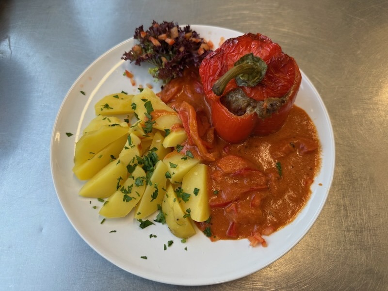 Caesar-Wrap mit Hähnchen, frischem Salat, Tomaten und Champignons, angerichtet auf einem Teller in der Hofküche auf Gut Tangstedt.
