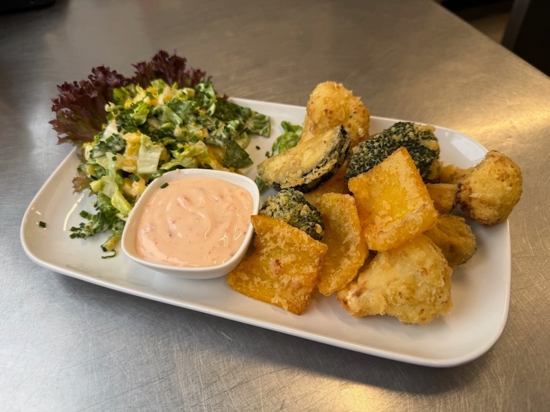 Knuspriges Gemüse-Tempura mit einer Auswahl an frittiertem Brokkoli, Blumenkohl und Kürbis, serviert mit einem cremigen Dip und frischem Blattsalat.