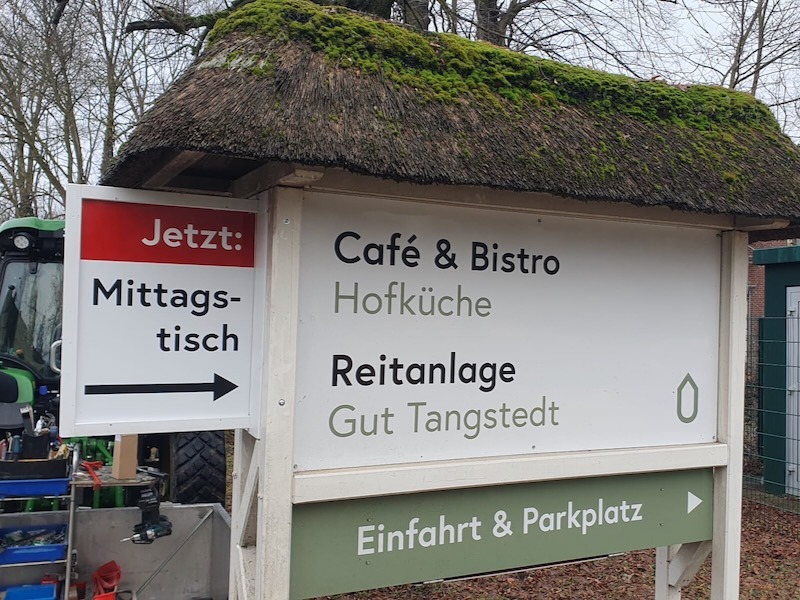 Hinweisschild an der Einfahrt zur Hofküche, das auf den wöchentlichen Mittagstisch aufmerksam macht.