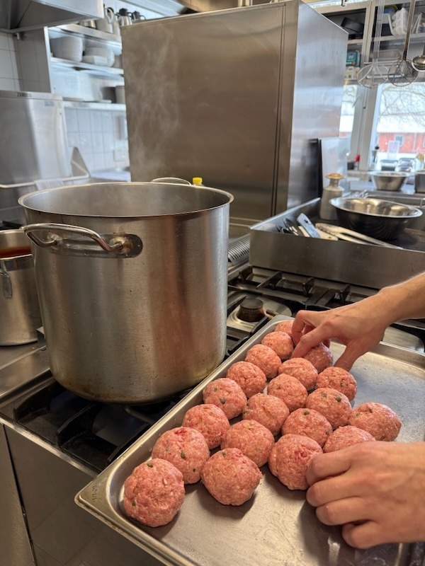 Vorbereitung von Königsberger Klopsen in der Gastro-Küche: Rohe Fleischbällchen mit sichtbaren Kapern werden auf einem Metallblech für das Kochen bereitgestellt.