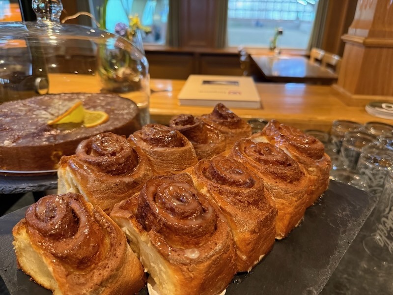 Frisch gebackene, hausgemachte Zimtschnecken mit feiner Zuckerglasur, ansprechend serviert auf einer Schieferplatte in einem Restaurant.