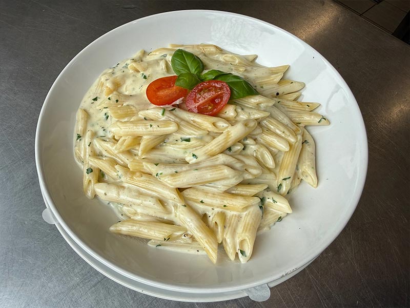 Ein herzhafter Pulled Beef Burger mit viel Sauce, roten Zwiebelringen und Salat, dazu eine Beilage aus hausgemachtem Coleslaw.