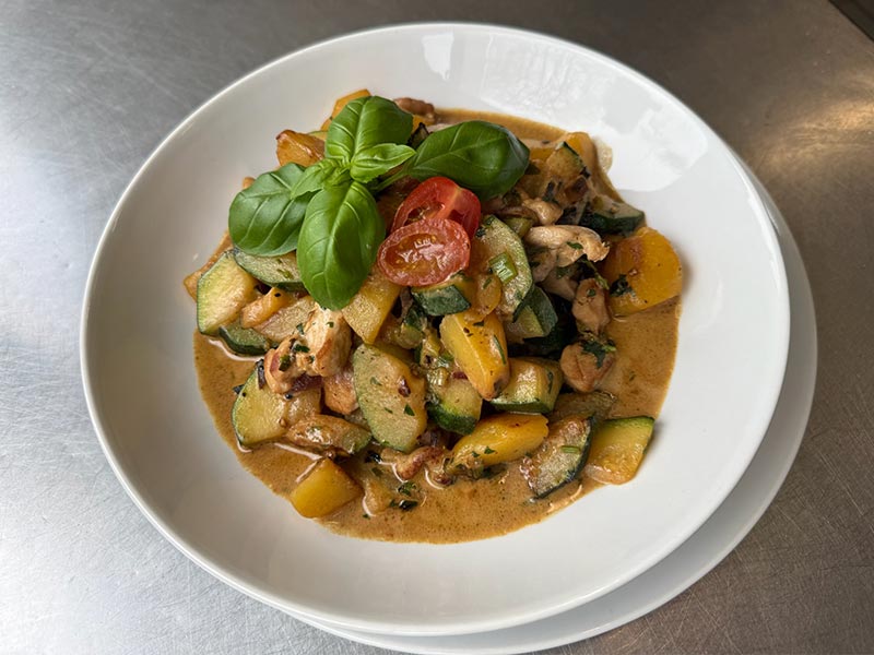 ampfende Gulaschsuppe mit reichlich Fleischeinlage und Pilzen, serviert mit drei Scheiben frischem Baguette.