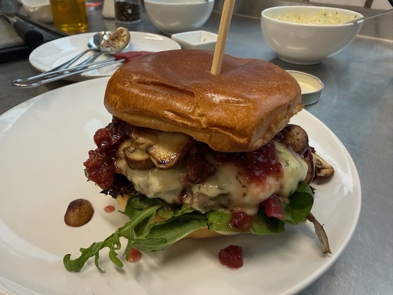 Brioche Brötchen, saftiges Rindfleisch, würziger Bergkäse,<br />
gebratene Pilze, hausgemachtes Zwetschgen-Apfel-Chutney,<br />
Waldkräuter-Senf-Mayo & Wildkräutersalat