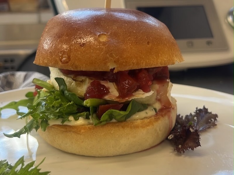 Brioche Brötchen, saftig überbackener Ziegenkäse,Honig-Apfelring, hausgemachtes Zwetschgen-Apfel-Chutney, Waldkräuter-Senf-Mayo & Wildkräutersalat