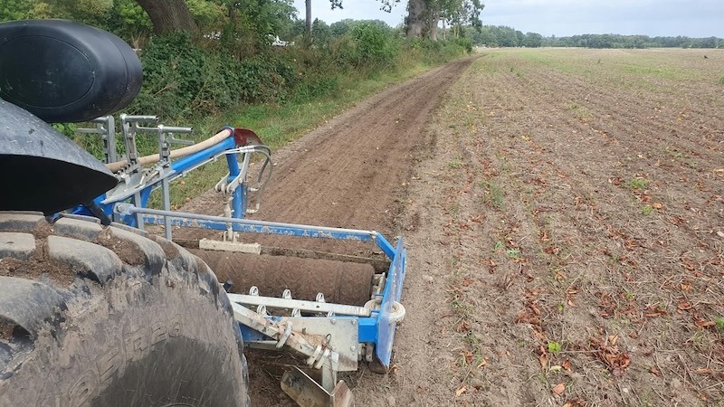 Reitwegepflege auf Gut Tangstedt: Traktor mit Tiefenlockerer und Rückverdichtungswalze auf einem Reitweg am Feldrand